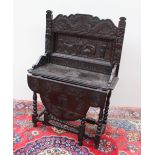 A 19th century low countries carved oak side table, the raised back carved with dragons, mermaids,