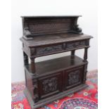 A 19th century carved oak buffet, the raised superstructure with a shelf and scrolling leaves,