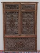 A Chinese carved screen, in the form of window shutters carved with figures, dogs of foo,