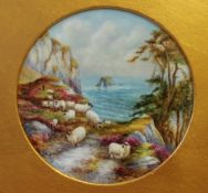 A Francis Clark porcelain plaque of circular form painted with sheep on a cliff edge with the sea