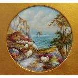 A Francis Clark porcelain plaque of circular form painted with sheep on a cliff edge with the sea