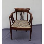 An Edwardian mahogany elbow chair of horseshoe shape with pierced splats and a pad seat on tapering