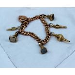 A yellow metal charm bracelet set with numerous charms including fobs and watch keys,
