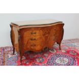 A continental burr walnut and mahogany commode with a serpentine top above three long drawers on
