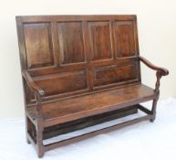 An 18th century oak settle with a six panelled back and solid seat on gun barrel front legs united