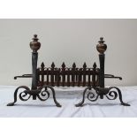 A pair of cast iron and bronze fire dogs, with a turned knop, tapering column and scrolling base,