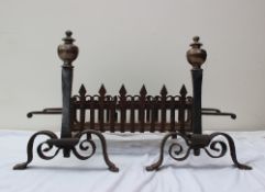 A pair of cast iron and bronze fire dogs, with a turned knop, tapering column and scrolling base,