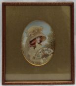 A painted silk and woolwork miniature depicting a young lady holding a fan,