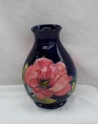 A Moorcroft pottery vase decorated in the Magnolia pattern to a blue ground,