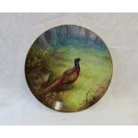 A Minton porcelain plate painted with a cock and hen pheasant in a woodland signed by A H Wright