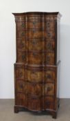 A reproduction walnut chest on chest with a moulded serpentine top above four long graduated