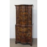 A reproduction walnut chest on chest with a moulded serpentine top above four long graduated