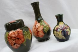 A Moorcroft pottery ginger jar and cover decorated in the hibiscus pattern to a green ground,