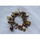 A 9ct yellow gold charm bracelet set with numerous charms including figures on a bench, speed boat,