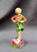 A Royal Worcester figure of a young girl in a kilt, standing on a heather landscape,