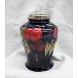 A Moorcroft wisteria / plums pattern vase, with an electroplated rim, to a dark blue ground,