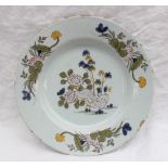 An 18th century Delft plate painted to the centre with flowers and bamboo,