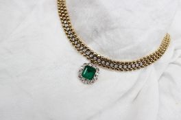 An 18ct yellow gold necklace set with an emerald and diamond pendant,