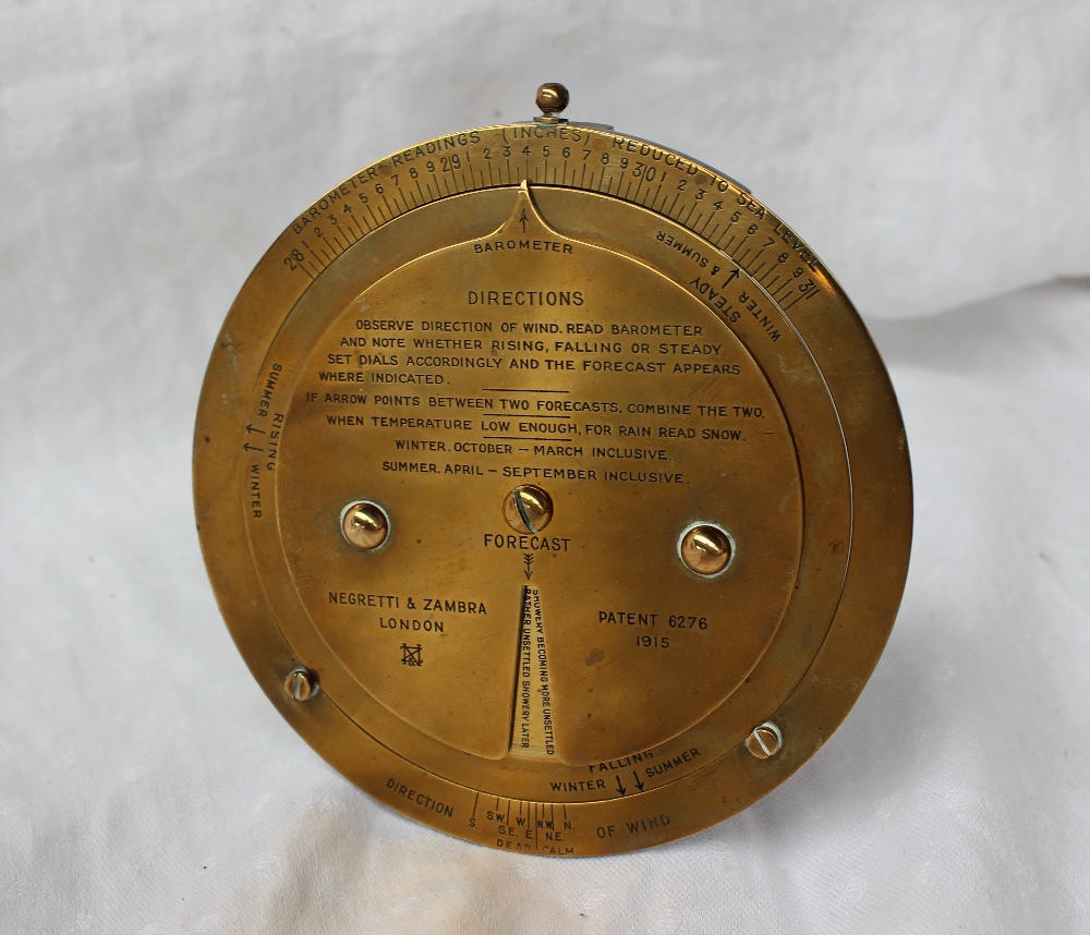 A Negretti and Zambra desk top brass barometer dial with a fixed outer rim for Barometer readings,