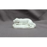 A 19th century porcelain figure of a reclining dog on an oval base,