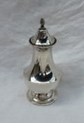 A George V silver sugar caster with a flame finial and a pierced top above a baluster body and a