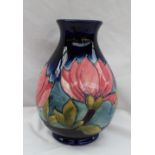 A Moorcroft pottery vase decorated in the Magnolia pattern to a blue ground,