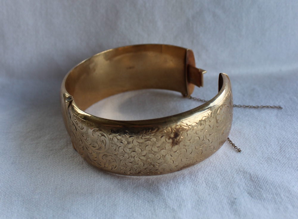 A 9ct yellow gold hinged bangle, with scrolling floral decoration, approximately 35.