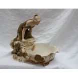 A Royal Dux pottery table centrepiece, depicting a maiden in a green dress leaning over a pond,