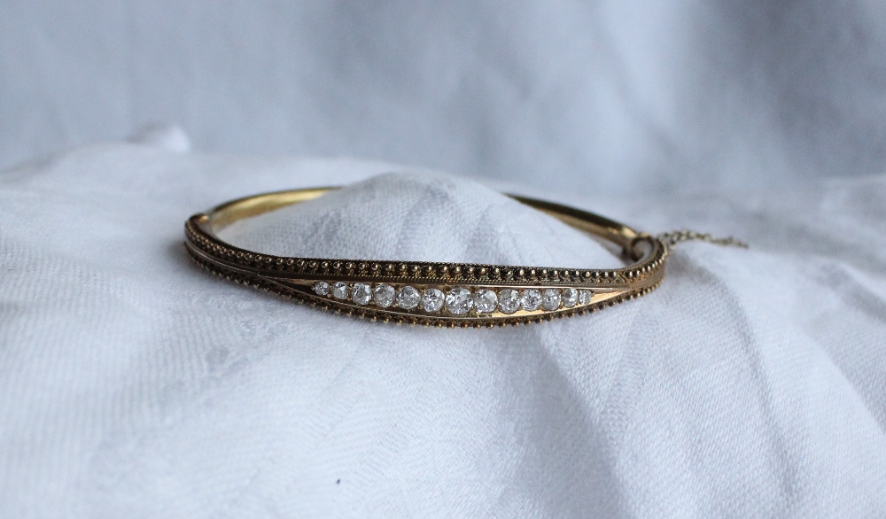 A Victorian diamond set hinged bangle set with thirteen round old cut diamonds to a yellow metal