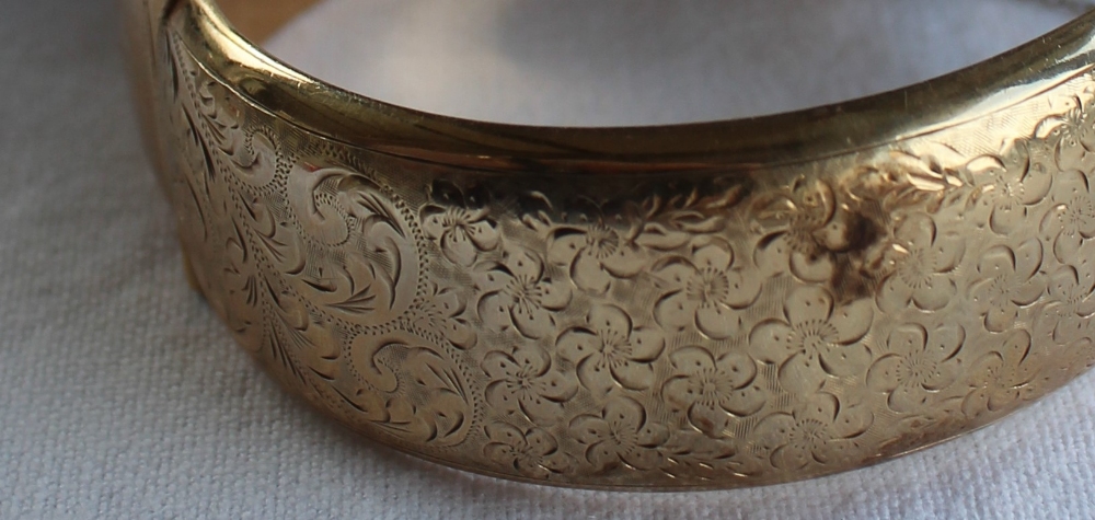 A 9ct yellow gold hinged bangle, with scrolling floral decoration, approximately 35. - Bild 2 aus 4