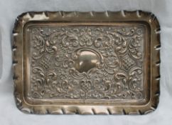 An Edward VII silver dressing table tray of rectangular form, embossed with scrolls and leaves,