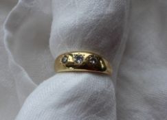 A three stone diamond ring set with three round old cut diamonds,