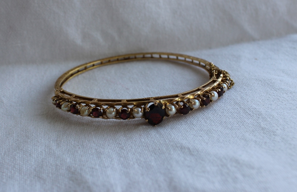 A Garnet and pearl set hinged bangle,