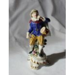 A 19th century porcelain seated figure, with a drum on his hip, in a gilt decorated blue tunic,