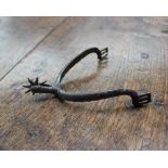A medieval steel rowel spur, with a freely moving wheel and diagonal line decoration,