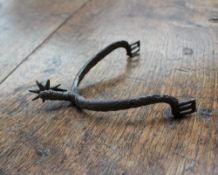 A medieval steel rowel spur, with a freely moving wheel and diagonal line decoration,