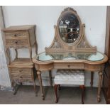 A limed oak dressing table together with a pair of limed oak bedsides cabinets and an upholstered