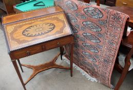 An early 20th century inlaid bureau together with a pink ground Turkoman rug