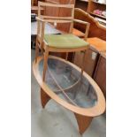 An oval teak glass topped coffee table together with a teak elbow chair
