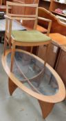 An oval teak glass topped coffee table together with a teak elbow chair