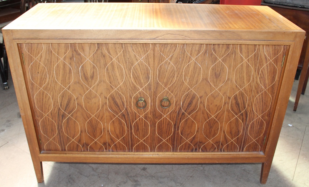 A 20th century teak sideboard with a rectangular top above a pair of cupboard doors with crossover