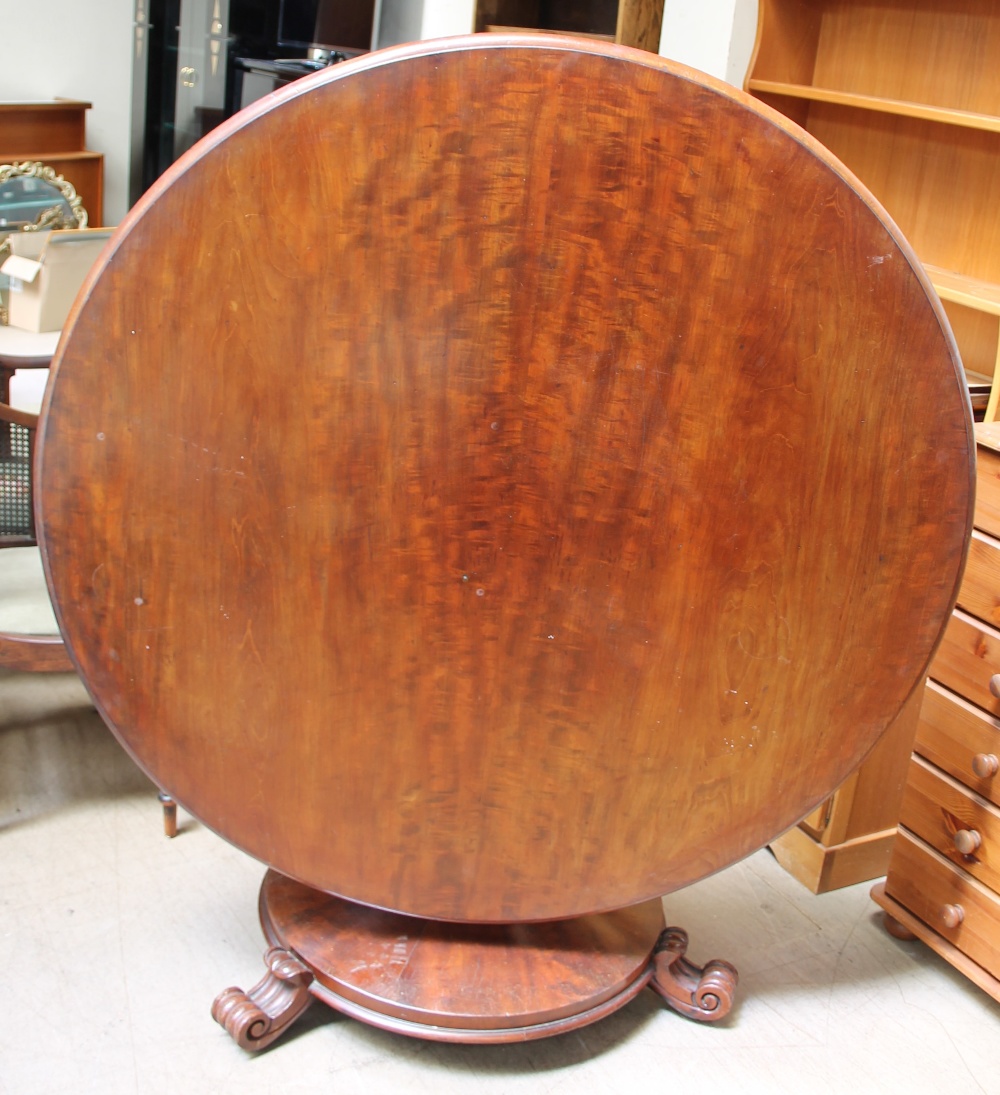 A Victorian mahogany supper table with a circular top above a tapering lotus leaf carved column,
