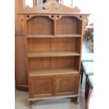 An Arts and crafts style bookcase with heart shaped piercing with shelves and cupboards on square