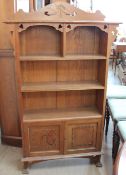 An Arts and crafts style bookcase with heart shaped piercing with shelves and cupboards on square