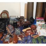 A mantle clock together with a collection of 35mm cameras, binoculars, shell cases,
