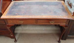 A 20th century mahogany desk with a rectangular top and two drawers on cabriole legs and pad feet