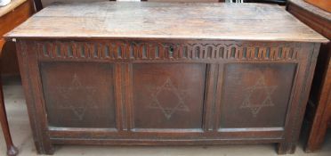 A large oak 18th century coffer with a planked top and a three panelled front on stiles