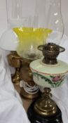 A painted opaque glass oil lamp together with two brass oil lamps,