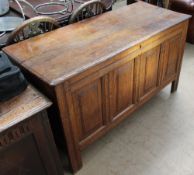 An 18th century oak coffer with a planked top above a four panelled front on stiles