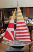 A model yacht with striped sails and a black and white hull,